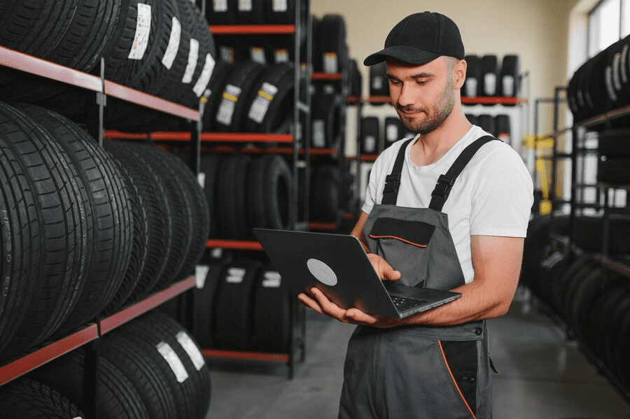 Confident mechanic man checking characteristics of tyre in auto service shop Confident mechanic man checking characteristics of tyre in auto service shop